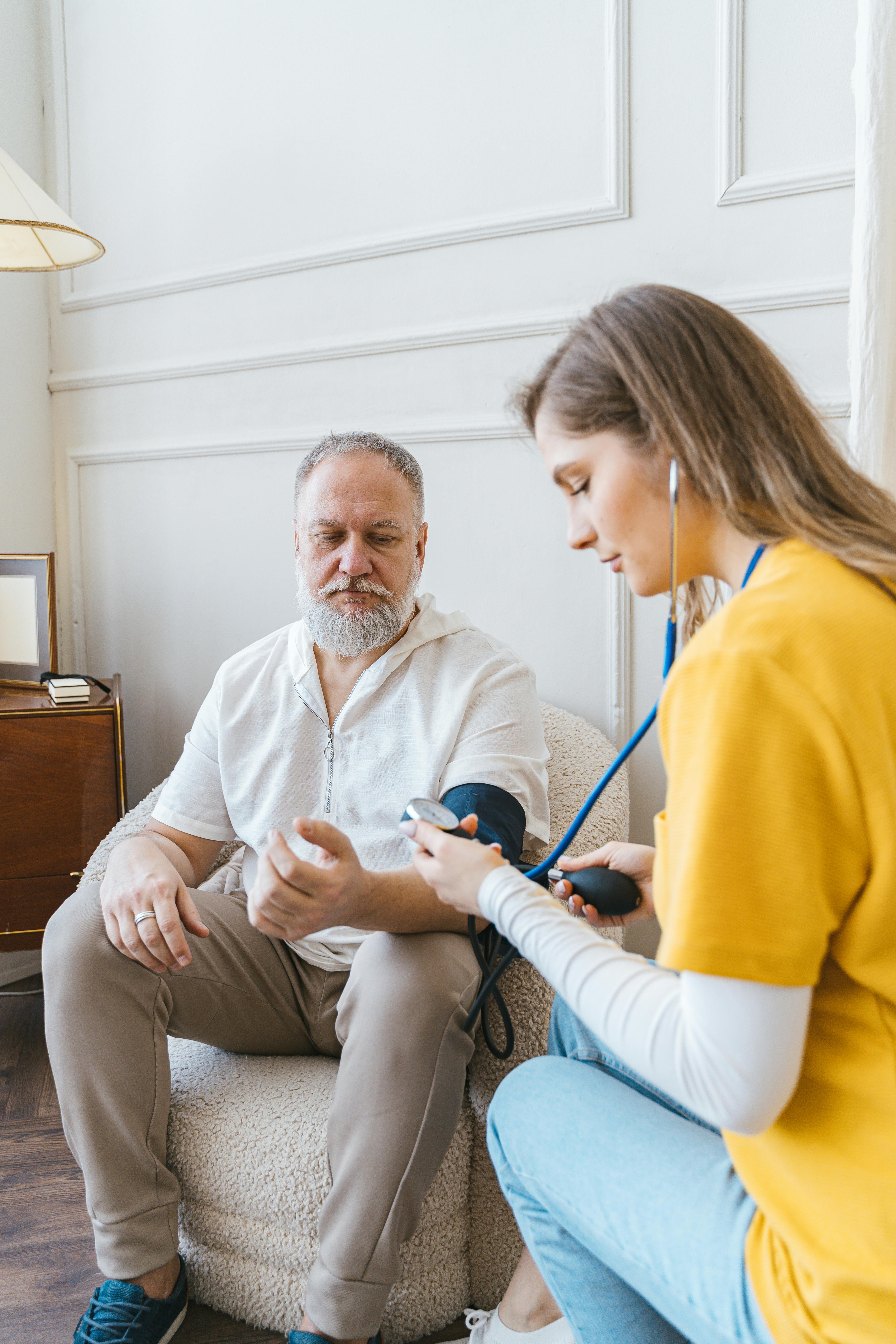 Caregiver taking blood pressure of elderly client during home care visit